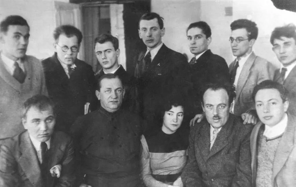 Фото участников Первого всесоюзного съезда советских писателей (1934). В первом ряду, слева направо: Александр Шевцов, Владимир Ставский, Маргарита Алигер, Александр Безыменский, Александр Исбах. Во втором ряду: Сергей Васильев, Григорий Бровман, Евгений Долматовский, Сергей Михалков, Александр Коваленков, Илья Френкель, Василий Сидоров.